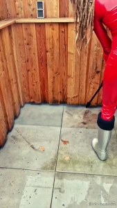 In hunter and red bodysuite clean the terrace with the pressure washer