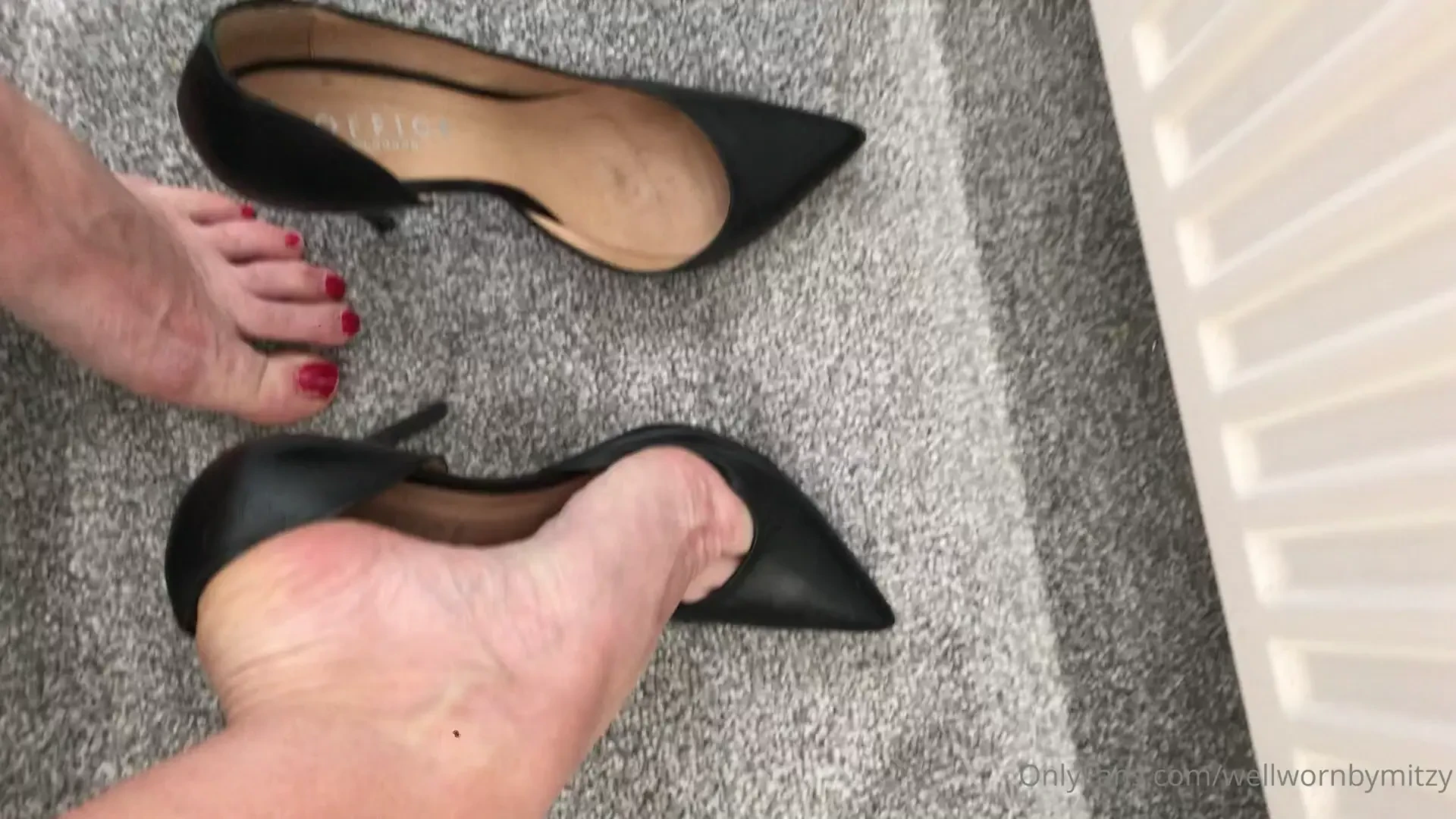 Black leather d orsay stilettos from office close up and dangling 