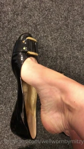 Black patent jimmy choo flats dangling close up of the well worn