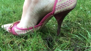 Pink heels sinking into the grass close up view