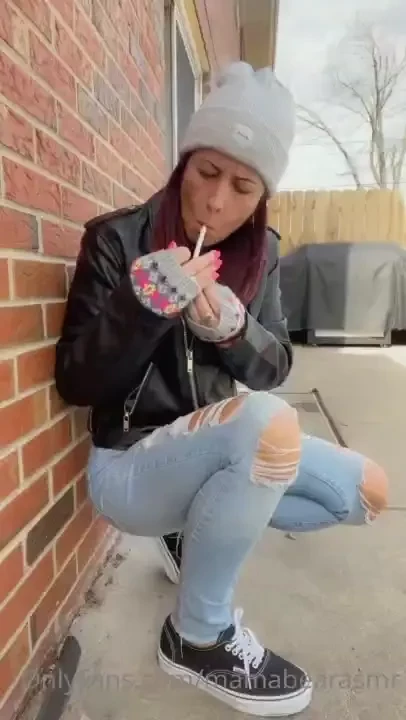 Smoking outside in leather jacket crushing cigarette 