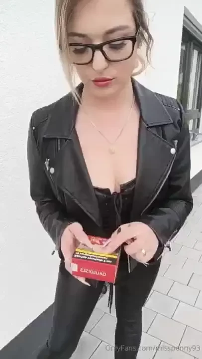 Smoking outside in a sexy full leather outfit crushing this cig with 