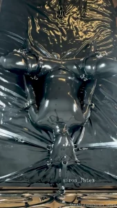 Rubber siron crucified on a rubber bed filled with pleasure bondage
