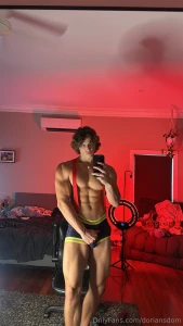 Mirror pose red backdrop turning up the heat topless muscles flexed