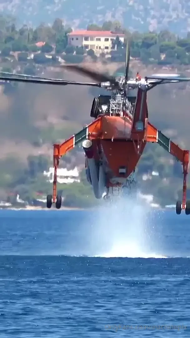 Firefighting s-64 air crane helicopter suctioning water with a 