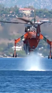 Firefighting s-64 air crane helicopter suctioning water with a